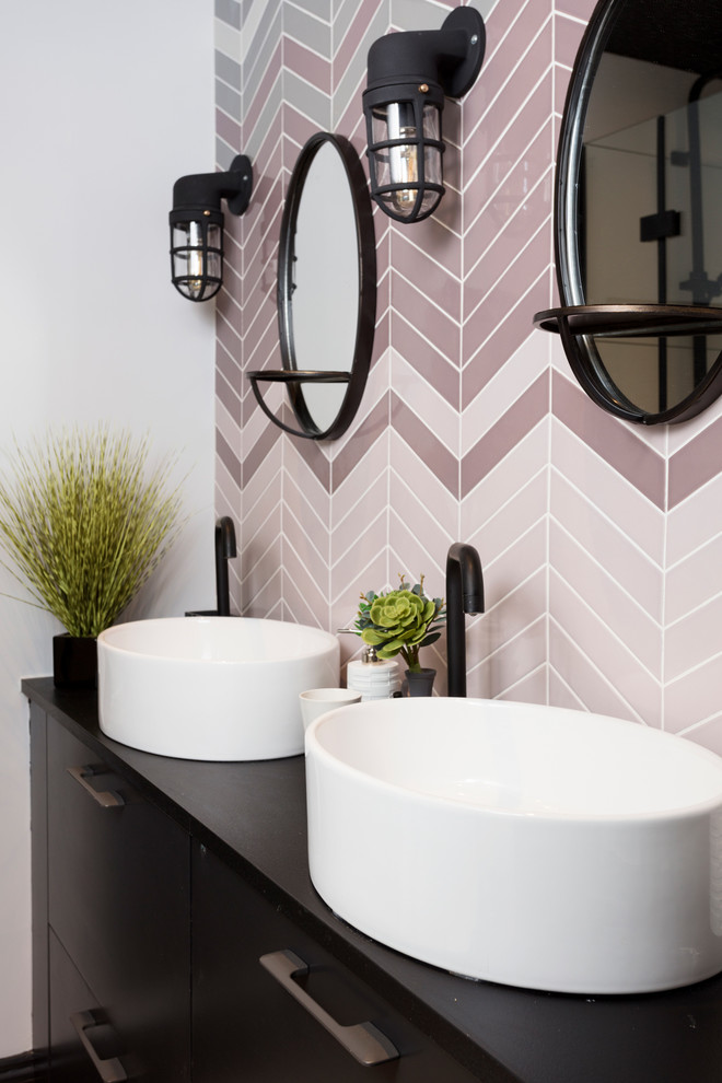 Immagine di una stanza da bagno minimal con lavabo a bacinella, ante lisce, ante nere, piastrelle rosa e top nero