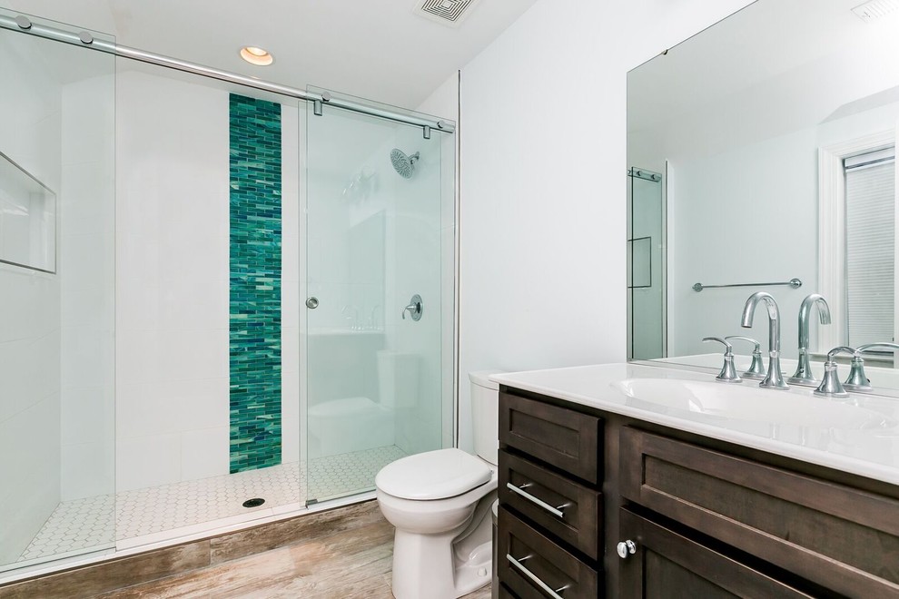 Example of a mid-sized classic 3/4 blue tile, green tile, white tile and porcelain tile medium tone wood floor walk-in shower design in Baltimore with recessed-panel cabinets, dark wood cabinets, a two-piece toilet, white walls, an integrated sink and solid surface countertops