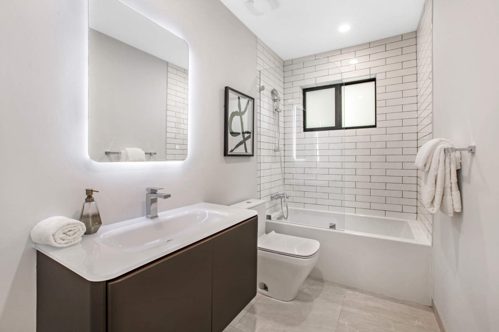 Inredning av ett modernt mellanstort vit vitt badrum, med släta luckor, bruna skåp, ett badkar i en alkov, vit kakel, tunnelbanekakel, en dusch/badkar-kombination, vita väggar, ett integrerad handfat, grått golv och med dusch som är öppen