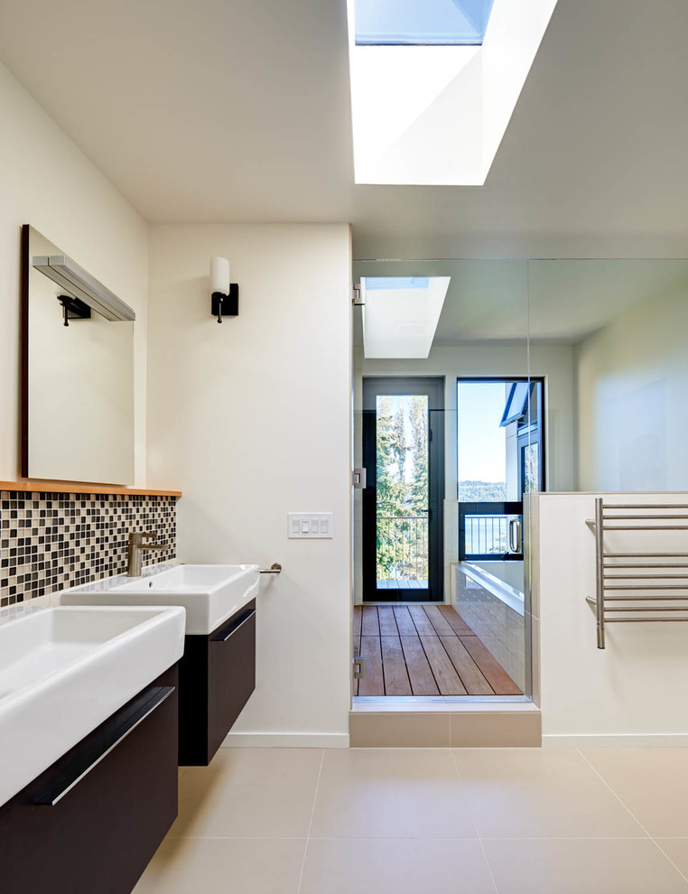 Свежая идея для дизайна: большая главная ванная комната в стиле модернизм с подвесной раковиной, плоскими фасадами, темными деревянными фасадами, накладной ванной, открытым душем, унитазом-моноблоком, бежевой плиткой, керамогранитной плиткой, белыми стенами и полом из керамогранита - отличное фото интерьера