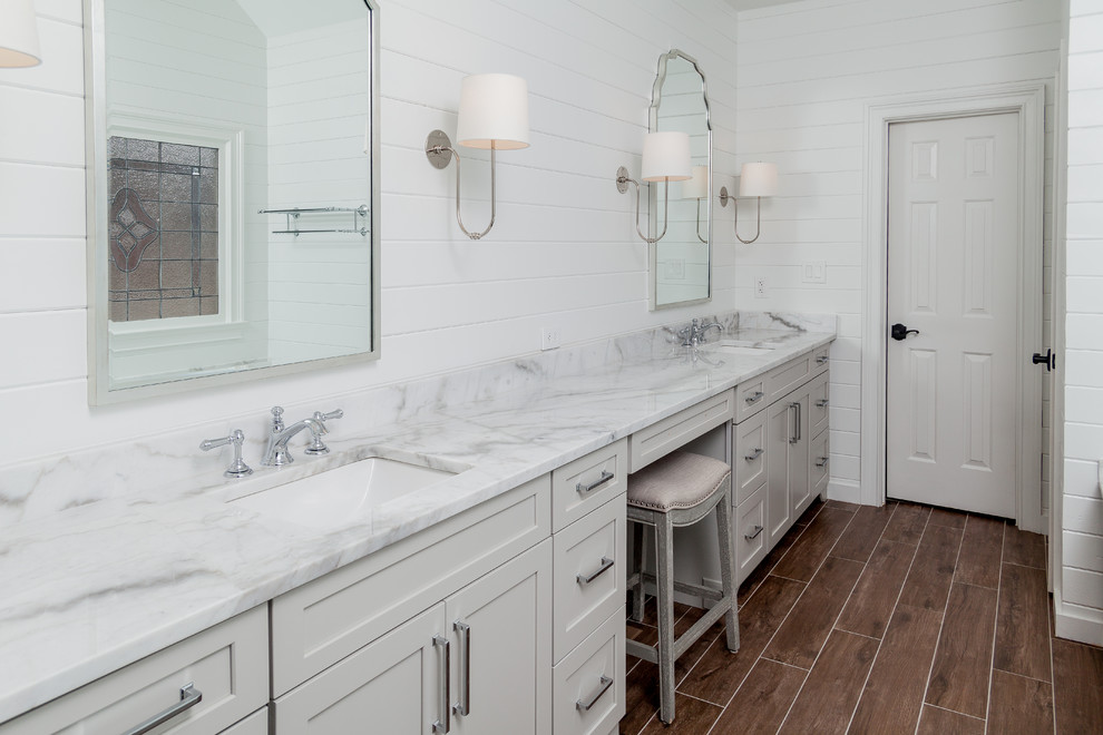 Пример оригинального дизайна: главная ванная комната среднего размера в стиле кантри с фасадами в стиле шейкер, серыми фасадами, полновстраиваемой ванной, открытым душем, раздельным унитазом, белой плиткой, керамической плиткой, белыми стенами, полом из керамогранита, врезной раковиной, мраморной столешницей, коричневым полом, душем с распашными дверями и белой столешницей