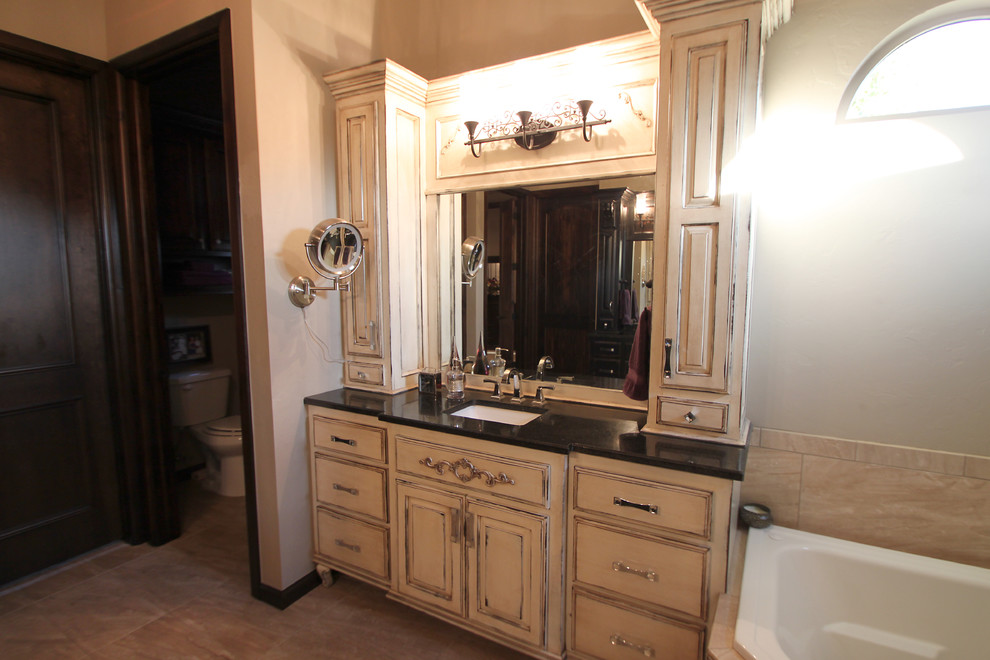 Example of a large trendy master multicolored tile and ceramic tile ceramic tile and multicolored floor bathroom design in Oklahoma City with shaker cabinets, distressed cabinets, a one-piece toilet, beige walls, an undermount sink and granite countertops