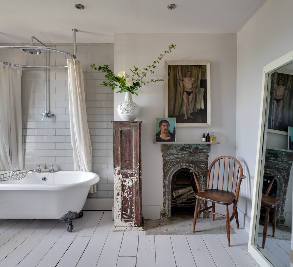 This is an example of a romantic bathroom in Kent with a claw-foot bath, a shower/bath combination, white tiles, metro tiles, white walls, painted wood flooring and a chimney breast.