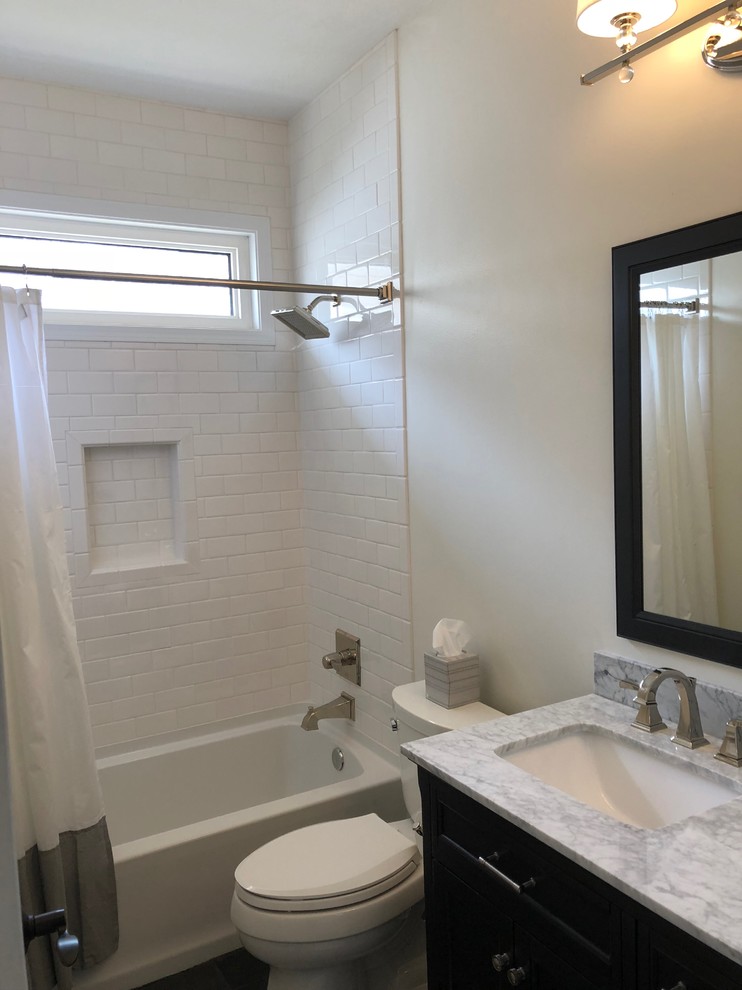 Medium sized classic shower room bathroom in Omaha with shaker cabinets, black cabinets, an alcove bath, an alcove shower, a two-piece toilet, white tiles, porcelain tiles, white walls, slate flooring, a submerged sink, quartz worktops, black floors, a shower curtain and grey worktops.