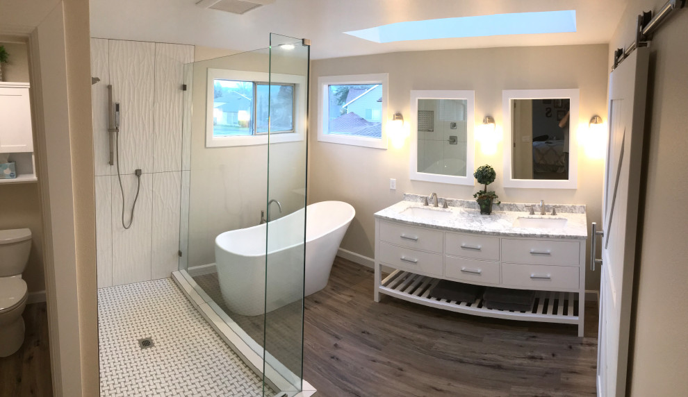 Photo of a medium sized classic ensuite bathroom in Seattle with freestanding cabinets, white cabinets, a freestanding bath, a corner shower, a two-piece toilet, white tiles, porcelain tiles, beige walls, vinyl flooring, a submerged sink, marble worktops, brown floors, an open shower and white worktops.
