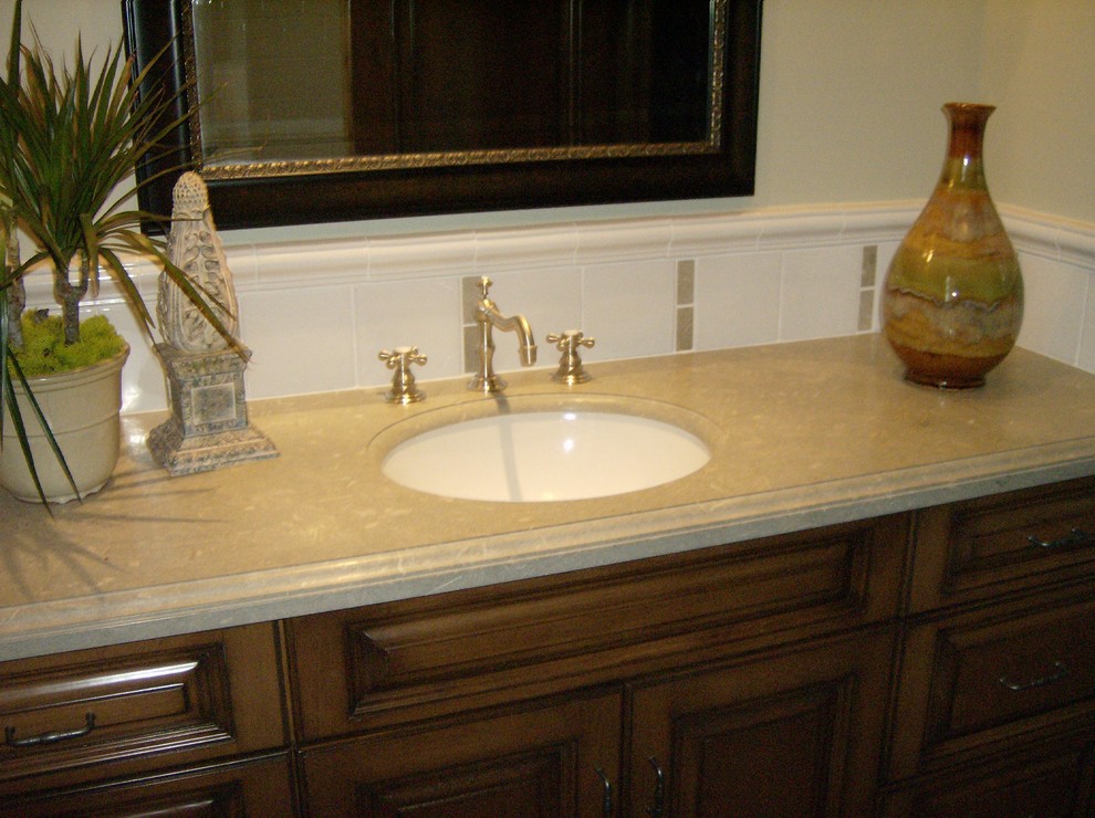 Exempel på ett mellanstort klassiskt badrum med dusch, med luckor med upphöjd panel, skåp i mörkt trä, beige kakel, vit kakel, porslinskakel, beige väggar, ett undermonterad handfat och bänkskiva i kalksten
