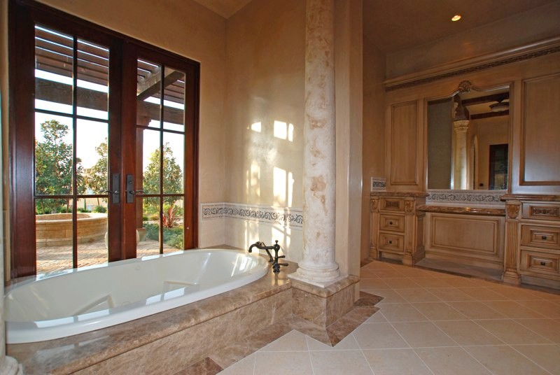 Foto di una grande stanza da bagno padronale stile rurale con ante con bugna sagomata, ante beige, vasca da incasso, pareti beige e pavimento in pietra calcarea