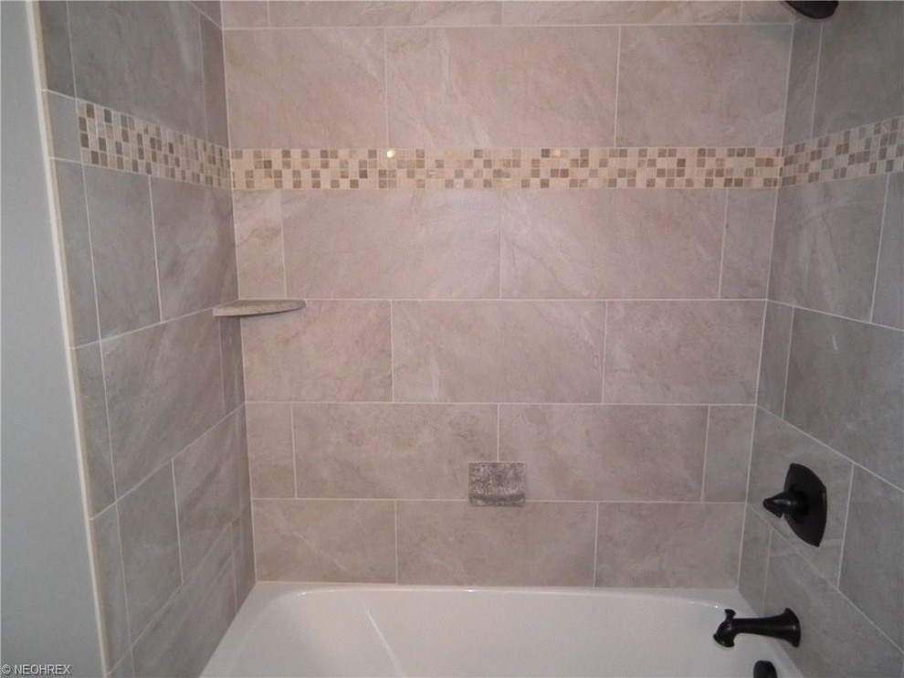 クリーブランドにある中くらいなトラディショナルスタイルのおしゃれな浴室 (アルコーブ型浴槽、シャワー付き浴槽	、グレーのタイル、磁器タイル、グレーの壁、磁器タイルの床) の写真