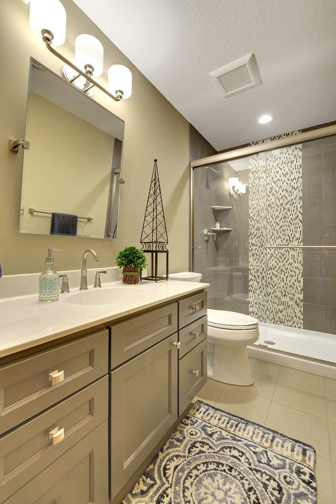 Medium sized traditional shower room bathroom in Minneapolis with recessed-panel cabinets, beige cabinets, an alcove shower, a two-piece toilet, grey tiles, white tiles, porcelain tiles, beige walls, ceramic flooring, an integrated sink, solid surface worktops, beige floors and a sliding door.