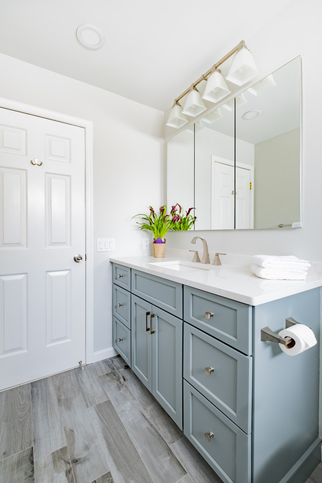 На фото: маленькая ванная комната в стиле неоклассика (современная классика) с фасадами в стиле шейкер, синими фасадами, накладной ванной, душем над ванной, раздельным унитазом, белой плиткой, керамогранитной плиткой, серыми стенами, полом из керамогранита, врезной раковиной, столешницей из кварцита, серым полом, шторкой для ванной и белой столешницей для на участке и в саду