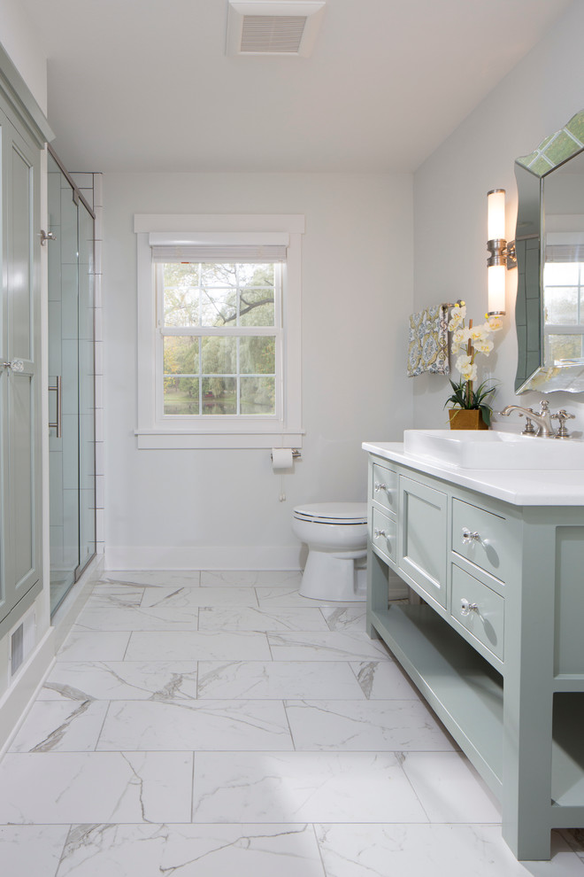 Klassisk inredning av ett stort badrum, med möbel-liknande, grå skåp, en kantlös dusch, en toalettstol med separat cisternkåpa, grå kakel, porslinskakel, grå väggar, marmorgolv, ett nedsänkt handfat och bänkskiva i kvarts