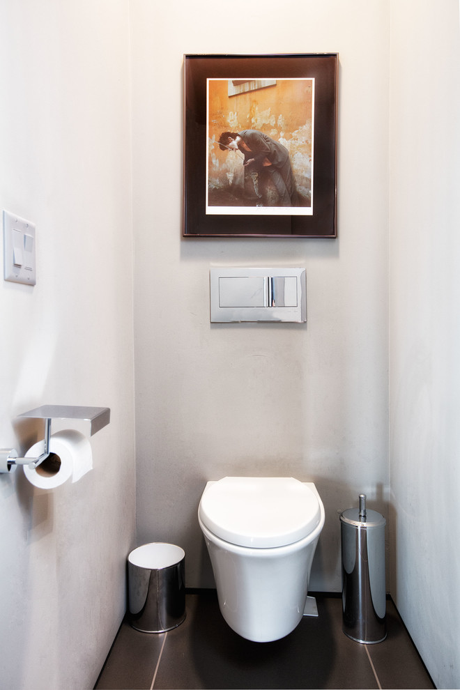Cette image montre un WC et toilettes minimaliste de taille moyenne avec WC à poser, un mur blanc, un sol en carrelage de céramique et un sol marron.