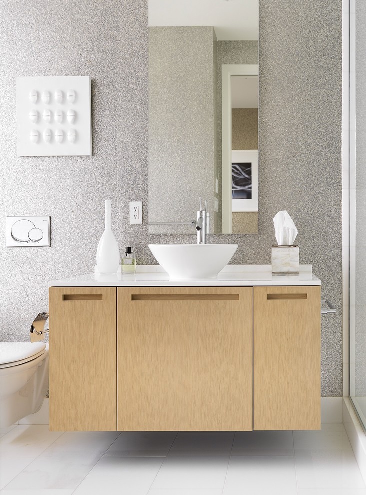 Inspiration pour une salle de bain design en bois clair avec une vasque, un placard à porte plane et un carrelage gris.