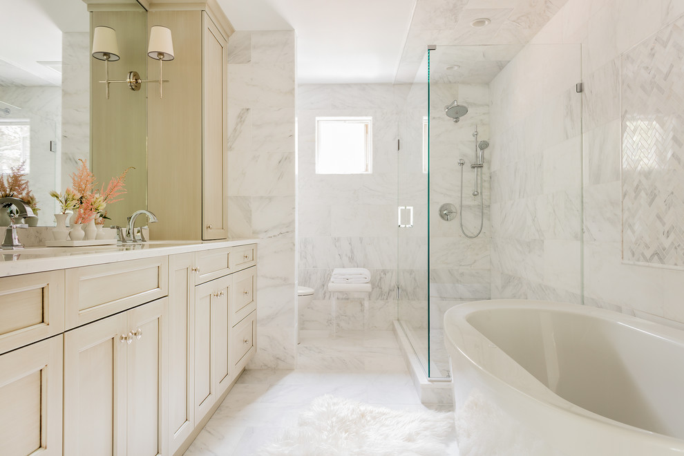 Идея дизайна: большая главная ванная комната в стиле неоклассика (современная классика) с фасадами с утопленной филенкой, бежевыми фасадами, отдельно стоящей ванной, двойным душем, унитазом-моноблоком, белой плиткой, удлиненной плиткой, полом из мозаичной плитки, монолитной раковиной и мраморной столешницей