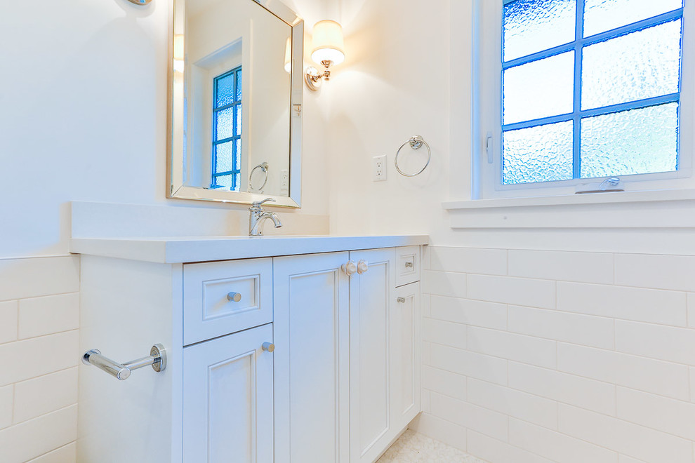 Diseño de cuarto de baño actual de tamaño medio con armarios estilo shaker, puertas de armario blancas, paredes blancas, suelo de baldosas tipo guijarro, aseo y ducha y lavabo bajoencimera
