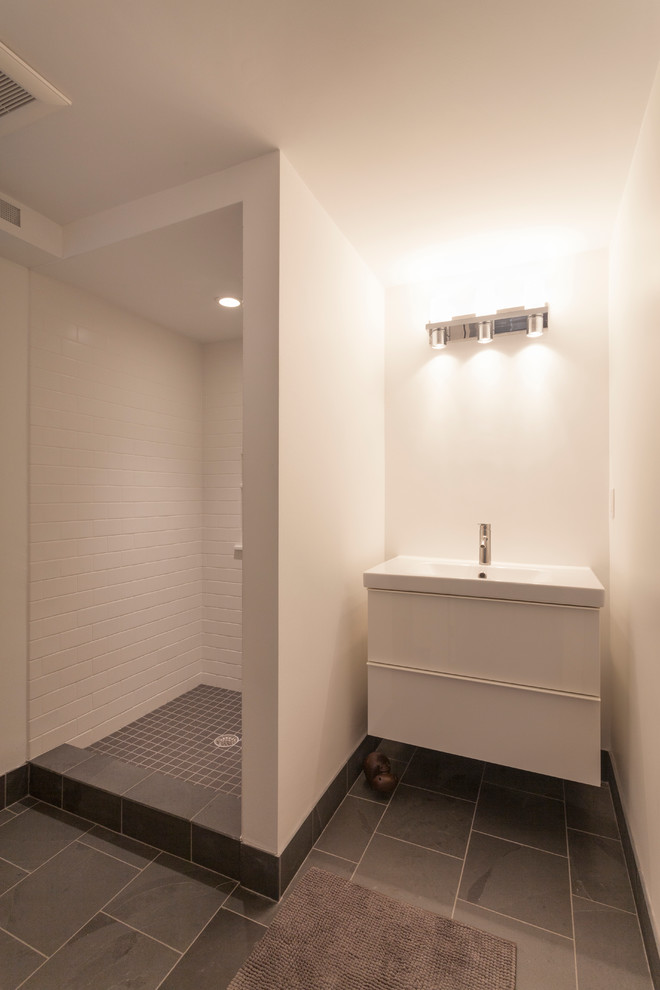 This is an example of a medium sized modern shower room bathroom in Boston with an integrated sink, flat-panel cabinets, white cabinets, an alcove shower, a two-piece toilet, white tiles, ceramic tiles, white walls and slate flooring.