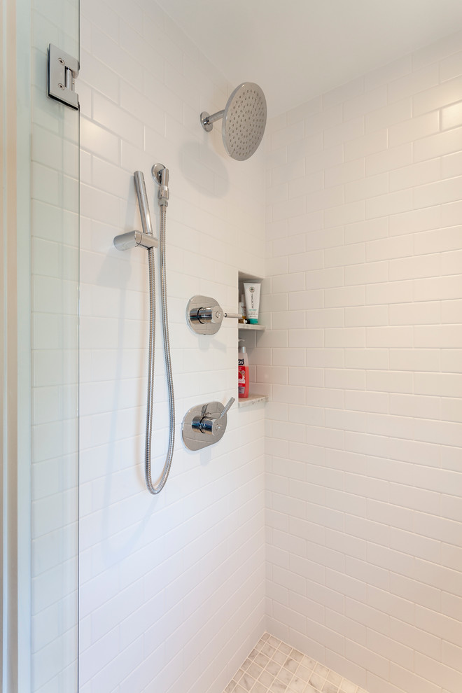 Foto på ett mellanstort funkis en-suite badrum, med ett integrerad handfat, släta luckor, vita skåp, en dusch i en alkov, en vägghängd toalettstol, vit kakel, keramikplattor, vita väggar och marmorgolv