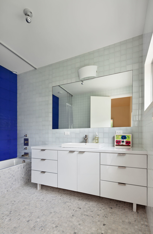 Modernes Badezimmer mit Einbauwaschbecken, flächenbündigen Schrankfronten, weißen Schränken, Badewanne in Nische, Duschbadewanne, blauen Fliesen, Marmorboden und Duschvorhang-Duschabtrennung in New York