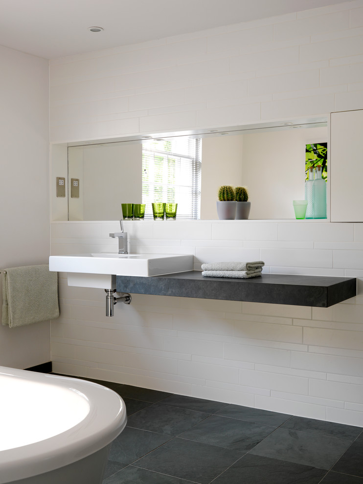 Imagen de cuarto de baño actual con lavabo suspendido, baldosas y/o azulejos blancos, paredes blancas y suelo de pizarra