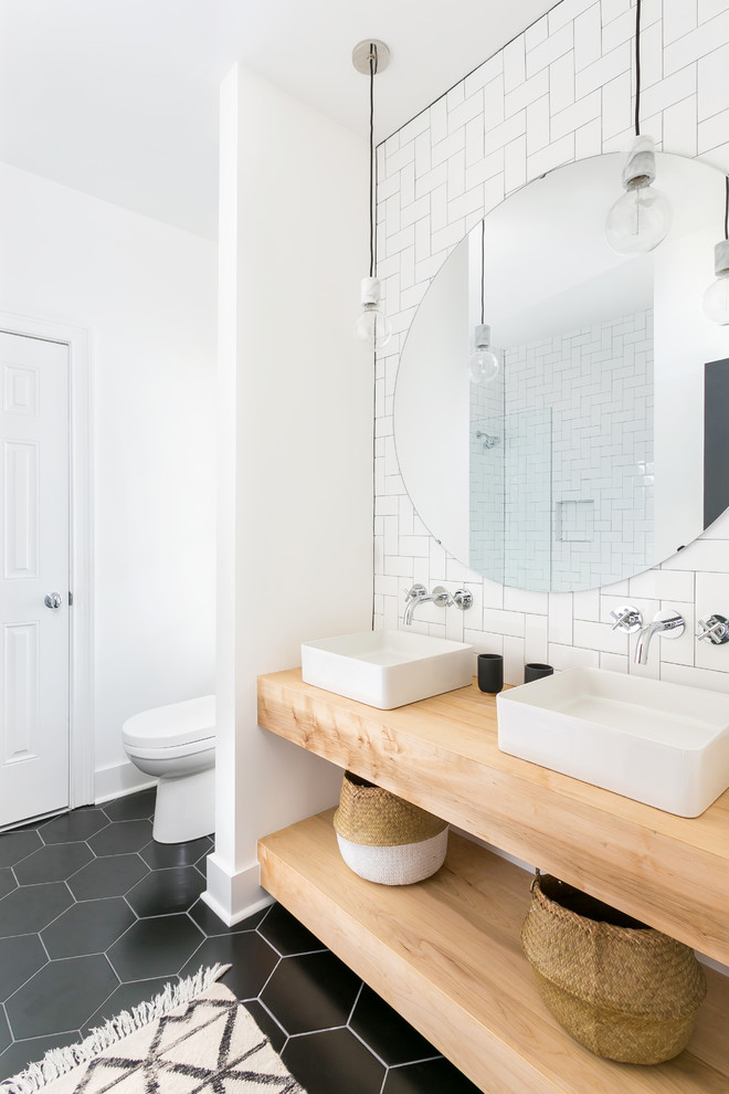 Exemple d'une salle de bain tendance avec un carrelage blanc, un carrelage métro, un mur blanc, une vasque, un plan de toilette en bois, un sol noir et un plan de toilette marron.