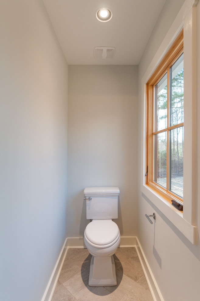 Inspiration for a mid-sized farmhouse ceramic tile and beige floor powder room remodel in Richmond with flat-panel cabinets, black cabinets, a two-piece toilet, white walls, an integrated sink and solid surface countertops