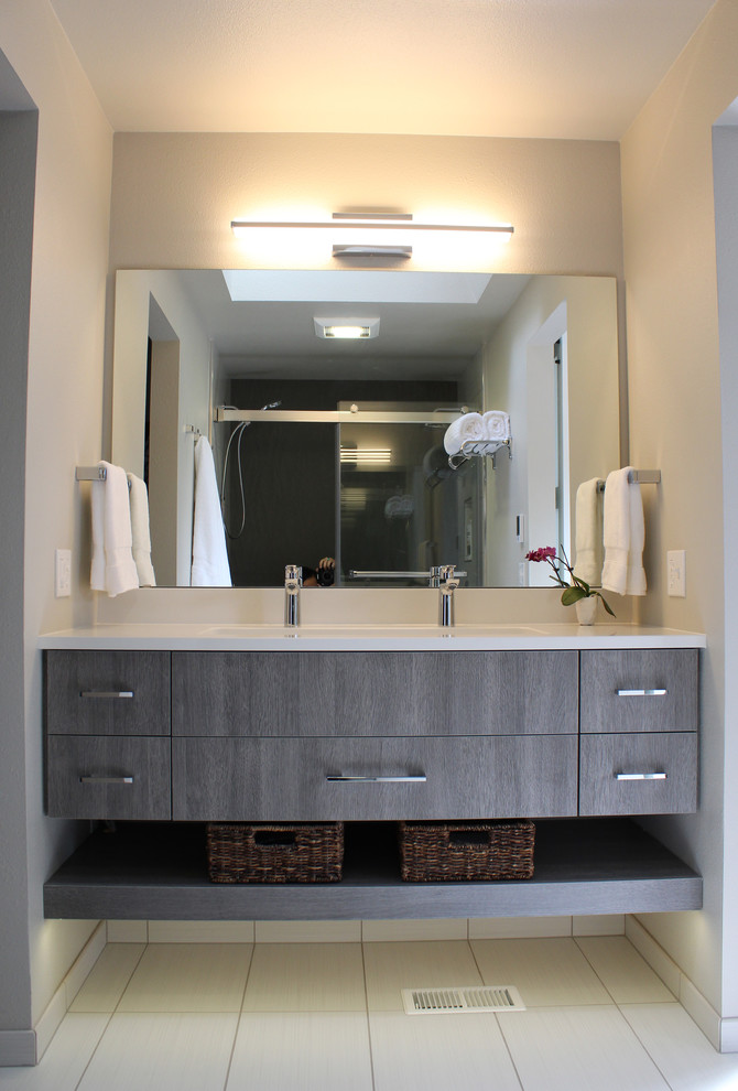 На фото: маленькая главная ванная комната в стиле модернизм с плоскими фасадами, серыми фасадами, двойным душем, унитазом-моноблоком, серой плиткой, керамической плиткой, серыми стенами, полом из цементной плитки, раковиной с несколькими смесителями, столешницей из искусственного кварца, серым полом, душем с раздвижными дверями и белой столешницей для на участке и в саду с