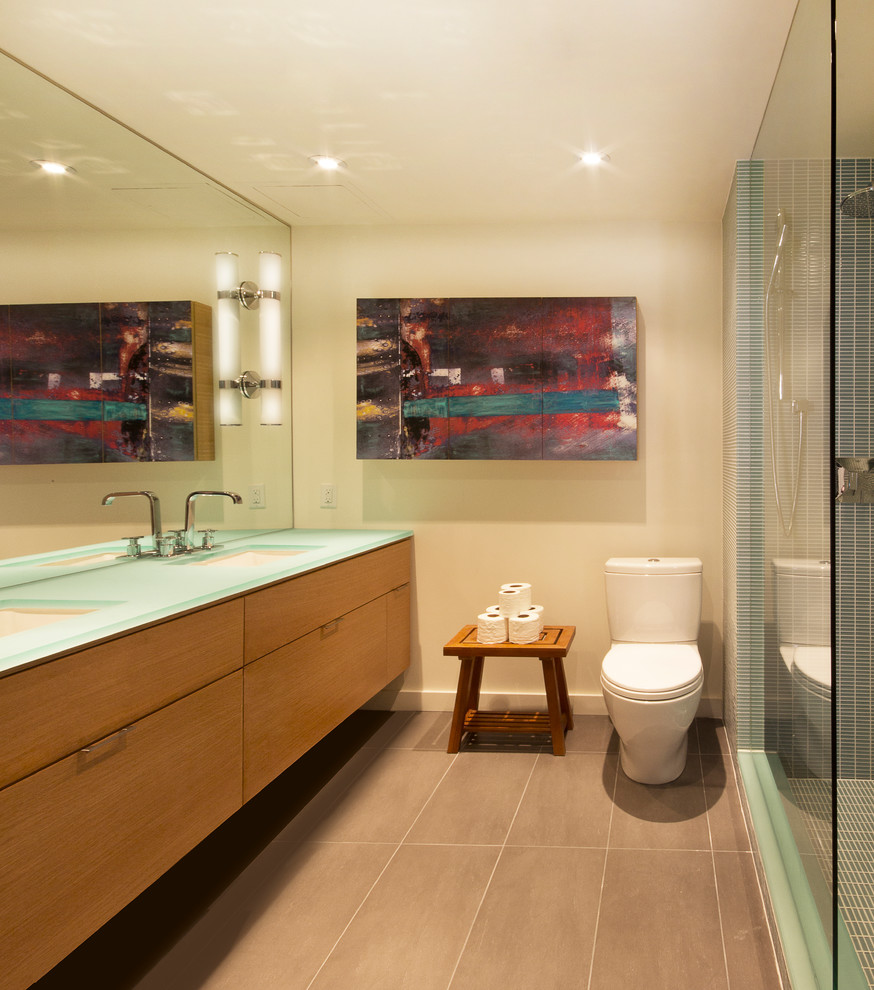 Photo of a medium sized modern ensuite bathroom in Toronto with a submerged sink, flat-panel cabinets, glass worktops, a walk-in shower, a two-piece toilet, blue tiles, glass tiles, white walls, porcelain flooring, medium wood cabinets and turquoise worktops.