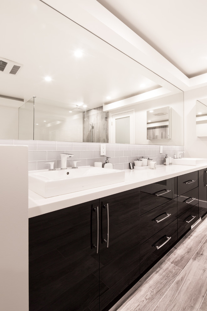 Photo of a large contemporary ensuite bathroom in Los Angeles with flat-panel cabinets, black cabinets, a built-in bath, a walk-in shower, a one-piece toilet, porcelain tiles, white walls, porcelain flooring, a built-in sink and engineered stone worktops.