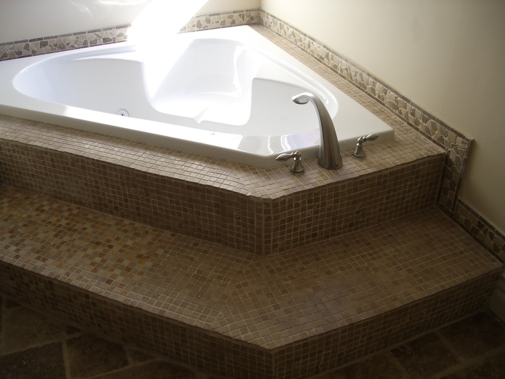 Immagine di una piccola stanza da bagno con doccia mediterranea con ante con bugna sagomata, ante in legno bruno, vasca da incasso, doccia alcova, WC monopezzo, piastrelle multicolore, piastrelle in pietra, pareti beige, pavimento in travertino, lavabo da incasso, top in cemento, pavimento multicolore, porta doccia a battente e top beige