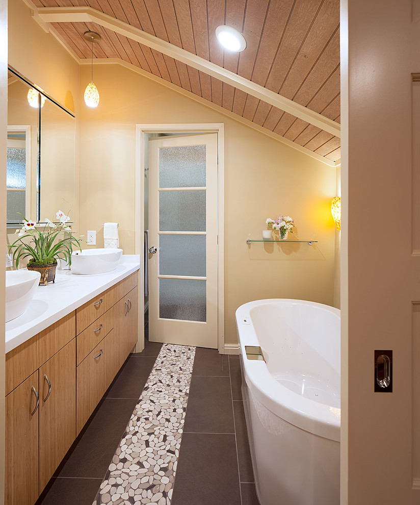 This is an example of a large coastal ensuite bathroom in San Francisco with a vessel sink, flat-panel cabinets, medium wood cabinets, solid surface worktops, a freestanding bath, an alcove shower, a two-piece toilet, brown tiles, porcelain tiles, yellow walls and porcelain flooring.