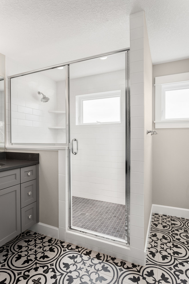 Идея дизайна: ванная комната среднего размера в современном стиле с фасадами с утопленной филенкой, серыми фасадами, душем в нише, раздельным унитазом, белой плиткой, плиткой кабанчик, бежевыми стенами, полом из керамогранита, душевой кабиной, врезной раковиной, столешницей из искусственного камня, разноцветным полом, душем с распашными дверями и серой столешницей