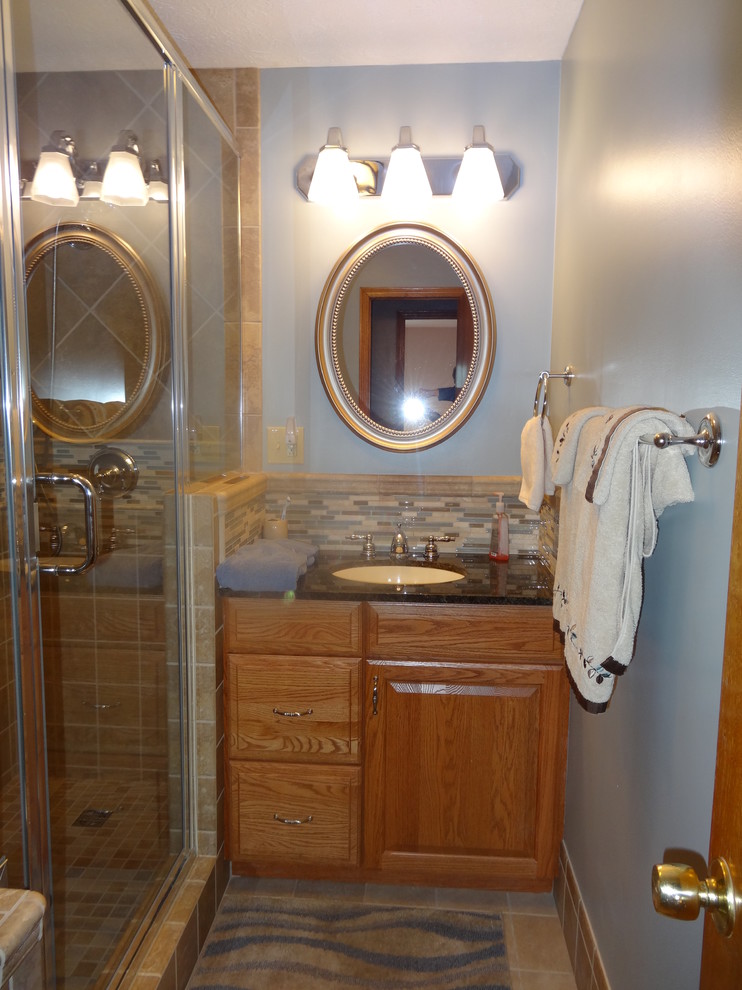 Modelo de cuarto de baño tradicional renovado con armarios con paneles con relieve, puertas de armario de madera oscura, encimera de granito y baldosas y/o azulejos beige