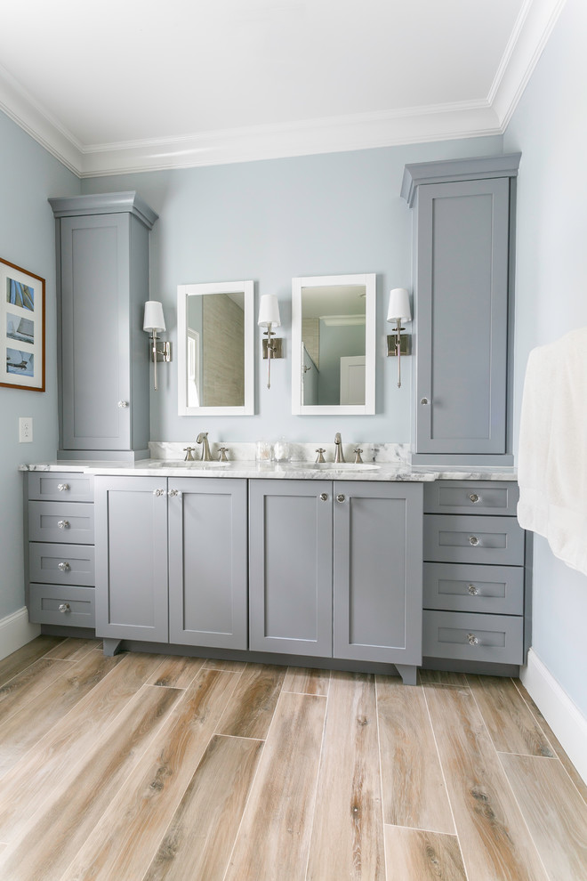 Idee per una stanza da bagno minimalista di medie dimensioni con ante in stile shaker, ante grigie, WC monopezzo, piastrelle beige, pareti blu, pavimento in legno massello medio, lavabo sottopiano, pavimento marrone e top bianco