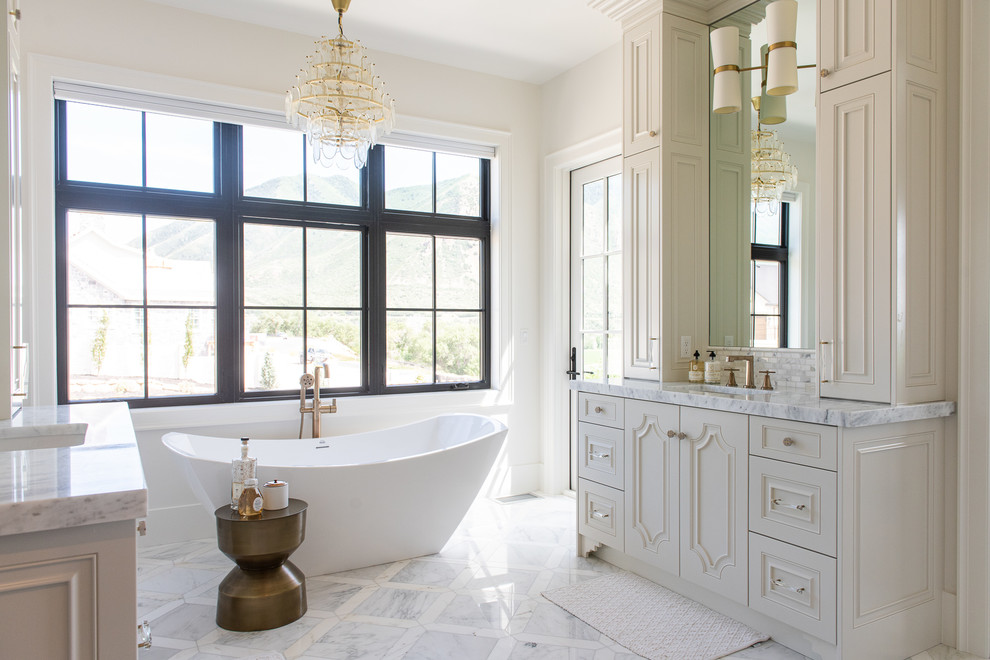 Immagine di una stanza da bagno country con ante bianche, vasca freestanding, pareti bianche, lavabo sottopiano, top bianco, ante con bugna sagomata e pavimento beige