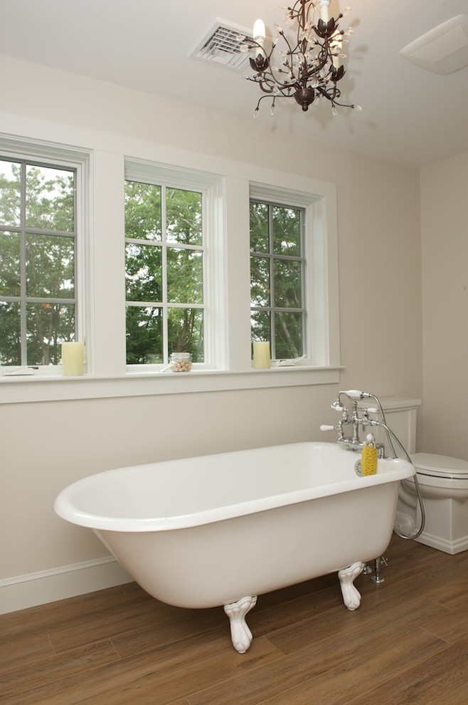 Klassisk inredning av ett mellanstort en-suite badrum, med ett badkar med tassar, en toalettstol med separat cisternkåpa och beige väggar