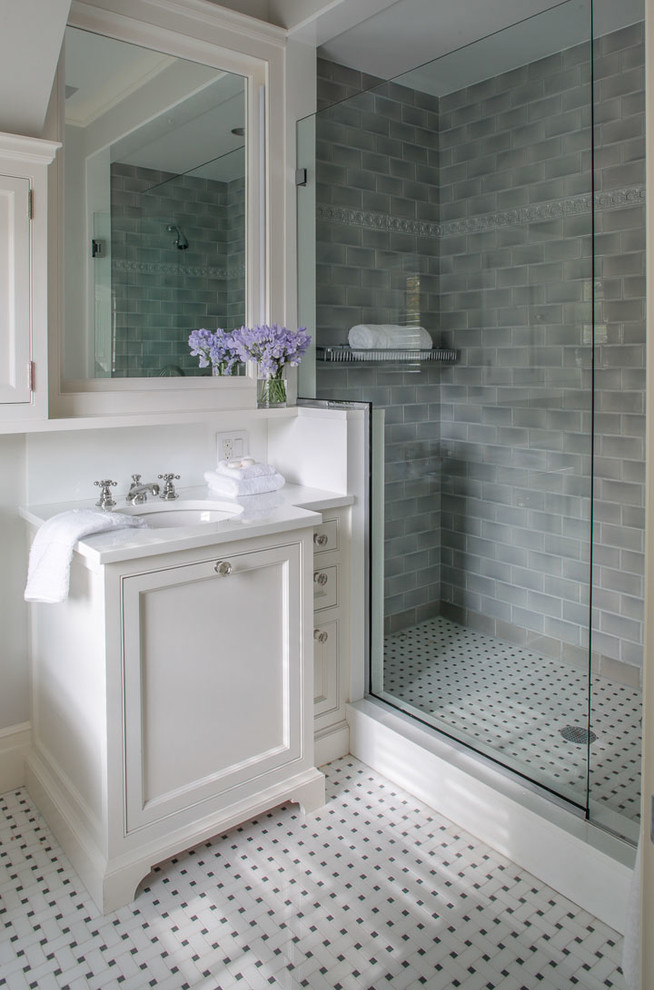 Inredning av ett klassiskt badrum med dusch, med luckor med infälld panel, vita skåp, en dusch i en alkov, grå kakel, tunnelbanekakel, vita väggar, ett undermonterad handfat, vitt golv och dusch med skjutdörr