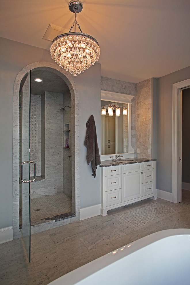 Idéer för att renovera ett stort vintage en-suite badrum, med luckor med upphöjd panel, vita skåp, ett fristående badkar, en dusch i en alkov, en toalettstol med hel cisternkåpa, beige kakel, porslinskakel, grå väggar, klinkergolv i porslin, ett undermonterad handfat, marmorbänkskiva, beiget golv och dusch med gångjärnsdörr