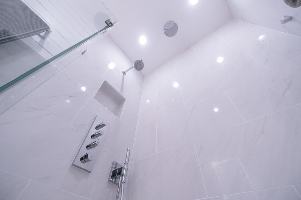 Inredning av ett modernt litet en-suite badrum, med släta luckor, bruna skåp, en dusch i en alkov, en vägghängd toalettstol, vit kakel, porslinskakel, vita väggar, klinkergolv i porslin, ett integrerad handfat, vitt golv och dusch med gångjärnsdörr