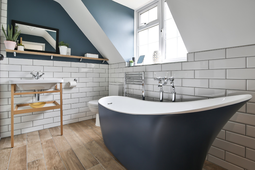 На фото: главная ванная комната среднего размера в современном стиле с отдельно стоящей ванной, белой плиткой, плиткой кабанчик, светлым паркетным полом, консольной раковиной, бежевым полом, унитазом-моноблоком и синими стенами с