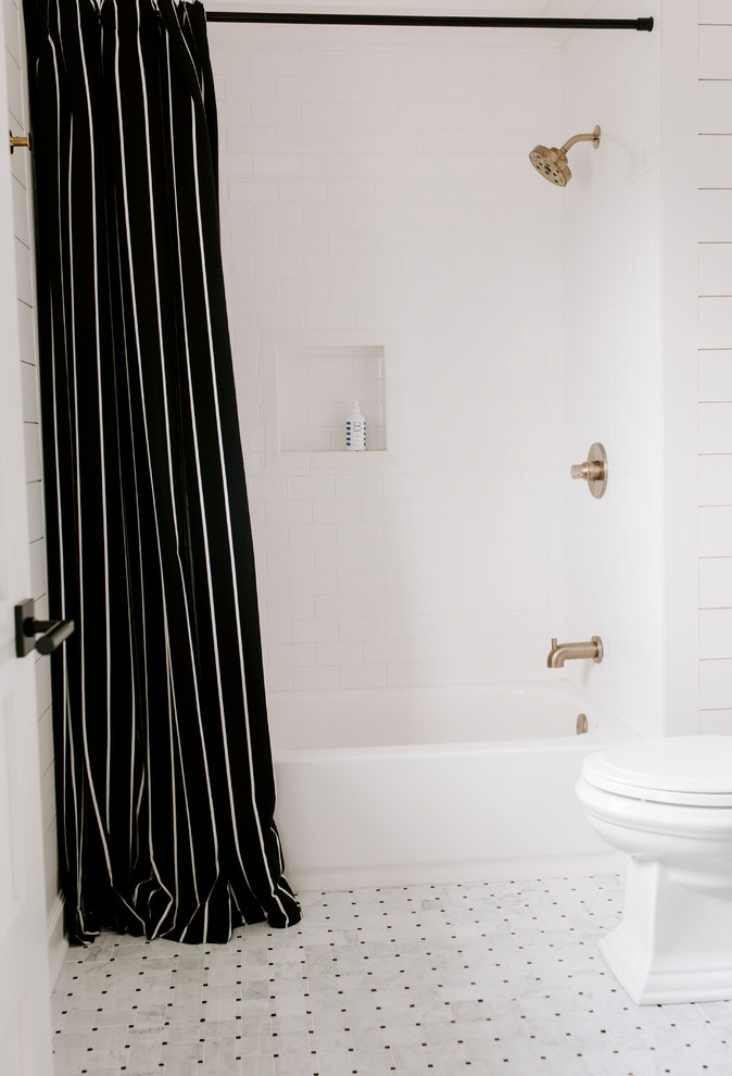 This is an example of a medium sized traditional family bathroom in Nashville with shaker cabinets, black cabinets, a built-in bath, an alcove shower, a one-piece toilet, white tiles, ceramic tiles, white walls, marble flooring, a submerged sink, marble worktops, white floors, a shower curtain and white worktops.