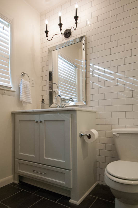 Idées déco pour une salle de bain craftsman avec un placard à porte shaker, des portes de placard blanches, un carrelage noir, un mur blanc et un plan de toilette en marbre.