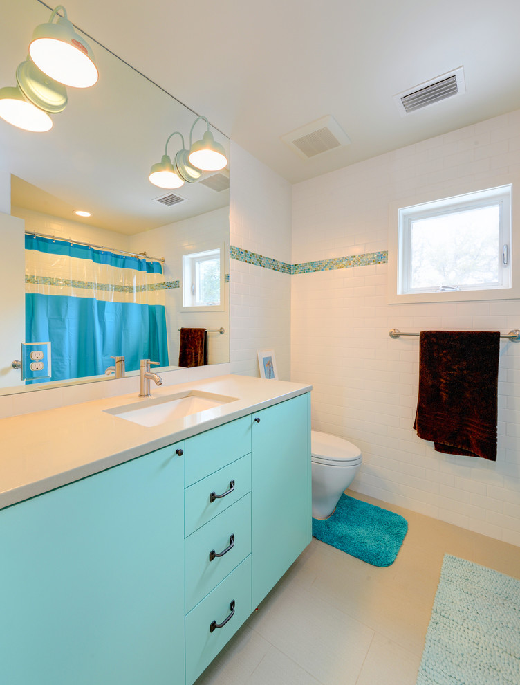 Foto di una stanza da bagno per bambini design di medie dimensioni con lavabo sottopiano, ante lisce, ante blu, top in quarzo composito, vasca/doccia, WC monopezzo, piastrelle bianche, piastrelle in ceramica, pareti bianche e pavimento con piastrelle in ceramica