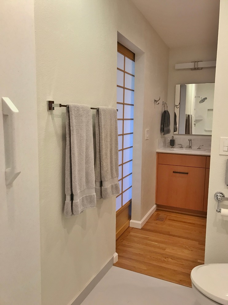 Foto på ett mellanstort orientaliskt en-suite badrum, med släta luckor, skåp i mellenmörkt trä, våtrum, en toalettstol med hel cisternkåpa, beige väggar, mellanmörkt trägolv, ett integrerad handfat och bänkskiva i akrylsten