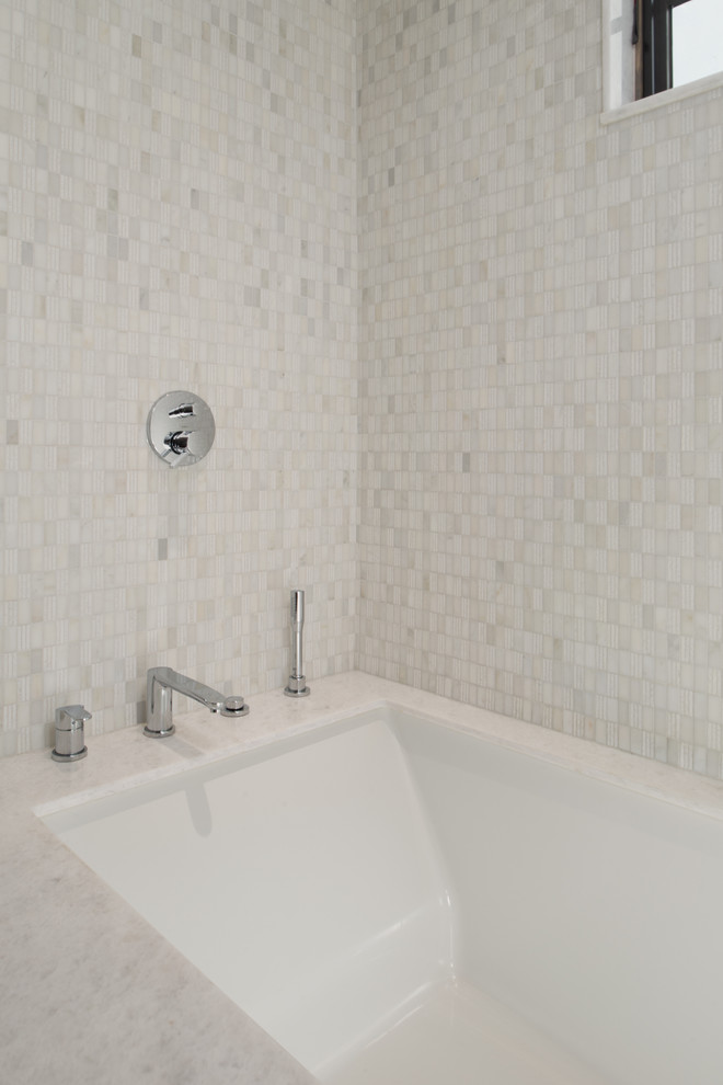 На фото: ванная комната в стиле неоклассика (современная классика) с ванной в нише, белой плиткой и каменной плиткой с