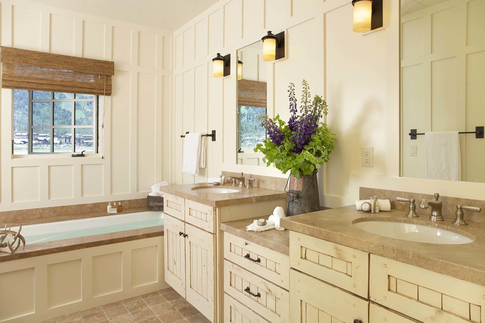 Diseño de cuarto de baño rural de tamaño medio con armarios estilo shaker, puertas de armario con efecto envejecido, bañera empotrada, paredes blancas, lavabo bajoencimera y suelo marrón
