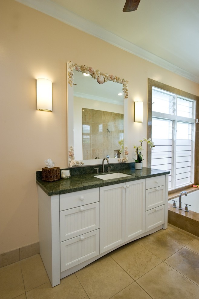 Cette photo montre une salle de bain exotique avec des portes de placard blanches, un plan de toilette en granite, un carrelage beige, des carreaux de porcelaine, un mur beige et un sol en carrelage de porcelaine.