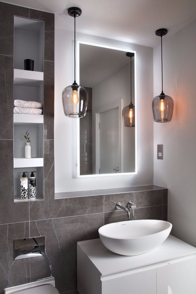 Modernes Badezimmer mit flächenbündigen Schrankfronten, weißen Schränken, grauen Fliesen, weißer Wandfarbe, Aufsatzwaschbecken, weißer Waschtischplatte und Einzelwaschbecken in London