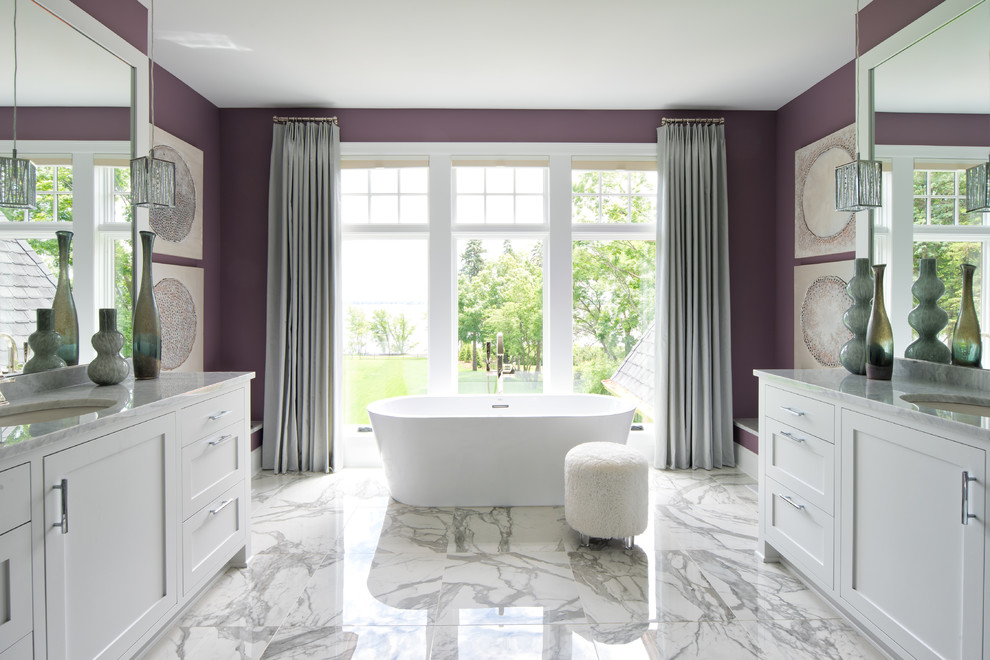 Пример оригинального дизайна: большая главная ванная комната в стиле неоклассика (современная классика) с фасадами в стиле шейкер, белыми фасадами, отдельно стоящей ванной, фиолетовыми стенами, мраморным полом, врезной раковиной, мраморной столешницей и серым полом