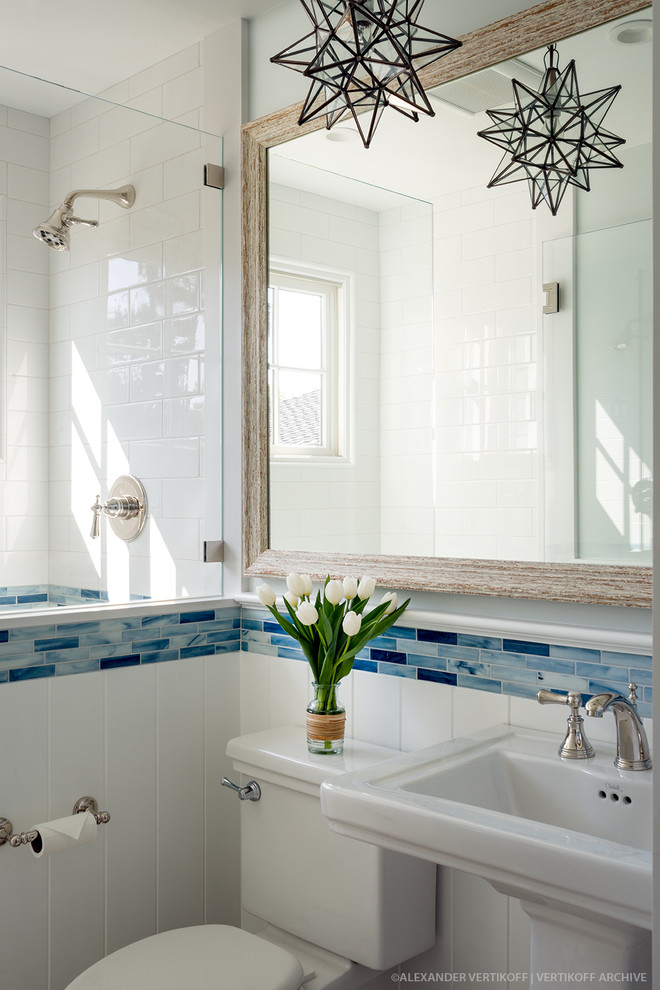Modelo de cuarto de baño costero pequeño con ducha empotrada, sanitario de dos piezas, baldosas y/o azulejos blancos, paredes azules, aseo y ducha y lavabo con pedestal