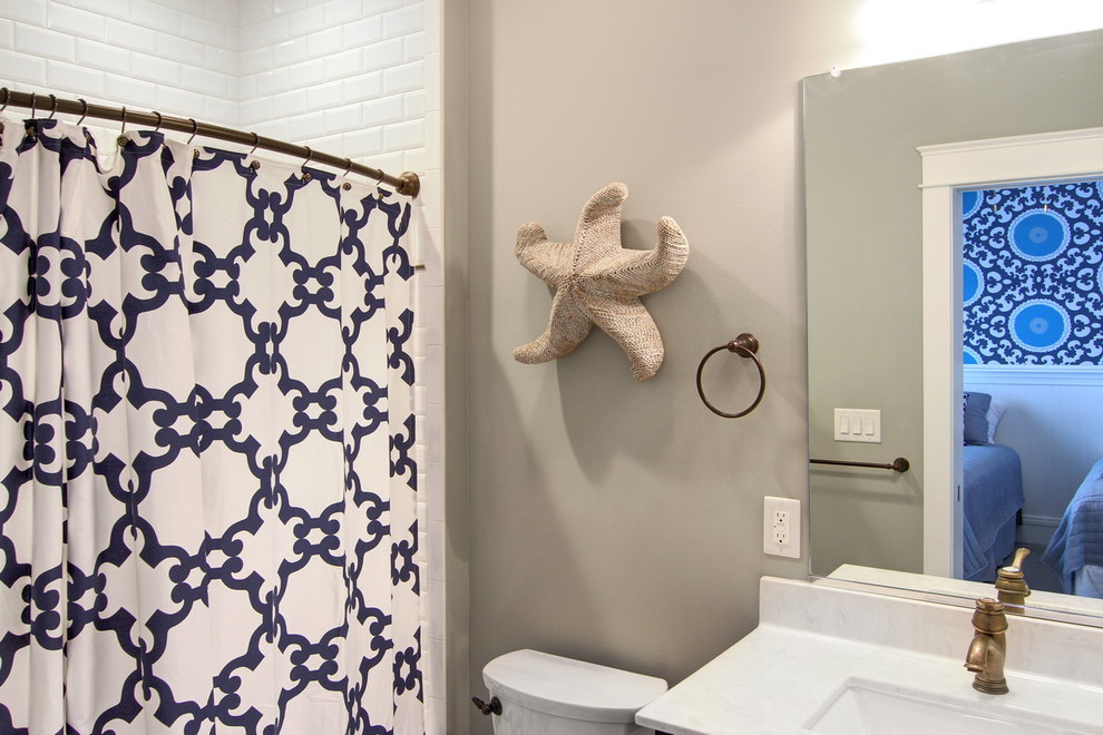 Maritim inredning av ett mellanstort badrum med dusch, med ett badkar i en alkov, en dusch/badkar-kombination, en toalettstol med separat cisternkåpa, vit kakel, tunnelbanekakel, grå väggar, ett undermonterad handfat och marmorbänkskiva